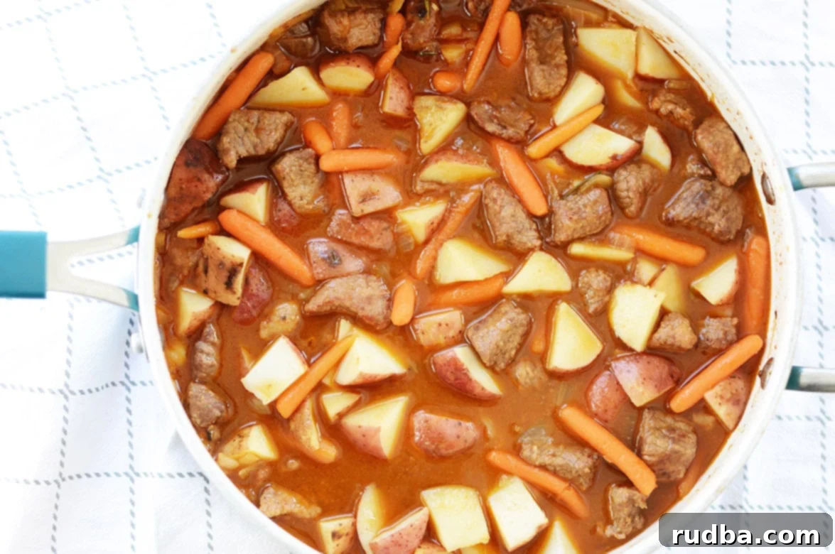 Hearty beef, potatoes, and carrots simmering in a vibrant blue pot, creating a comforting stew.