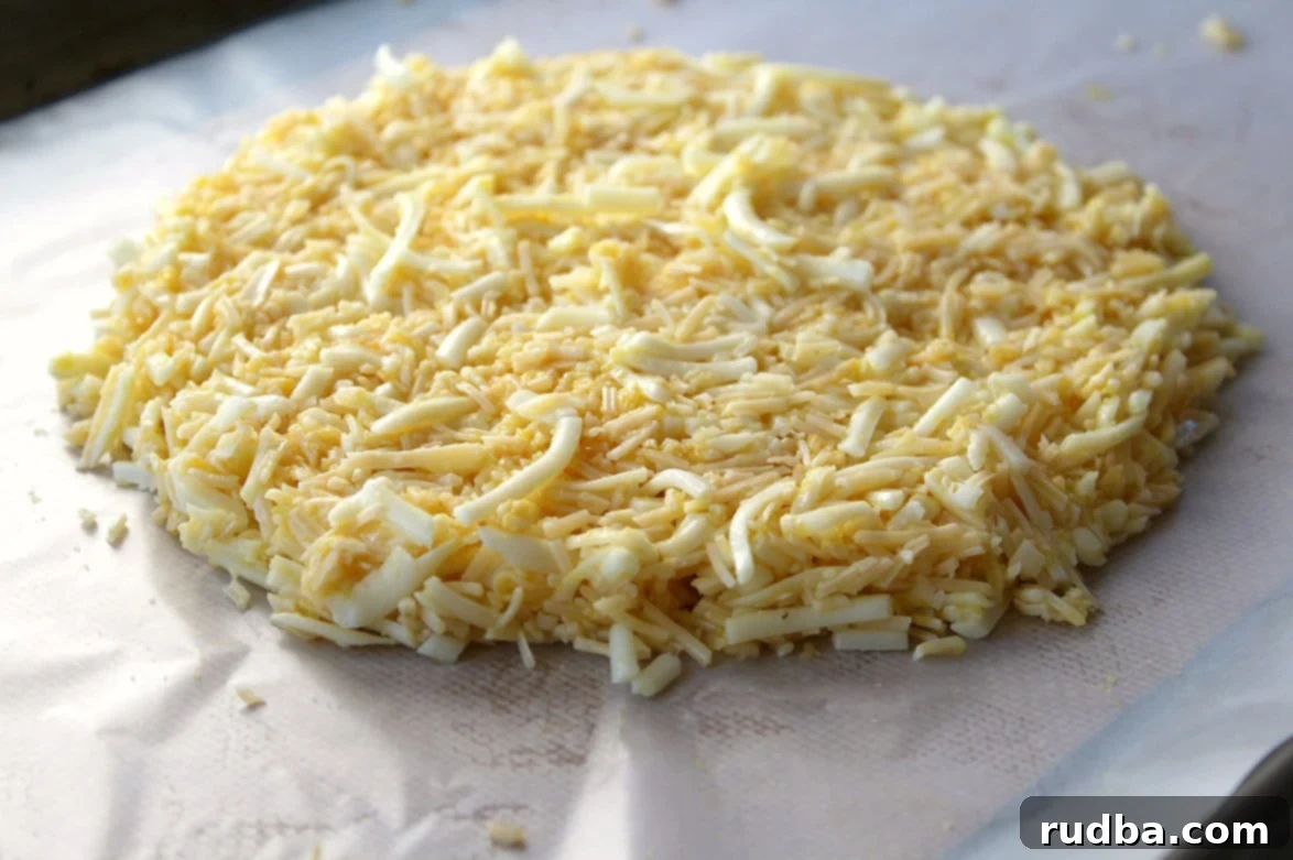 Raw keto cheese bread mixture flattened on a baking sheet lined with parchment paper, ready for the oven.