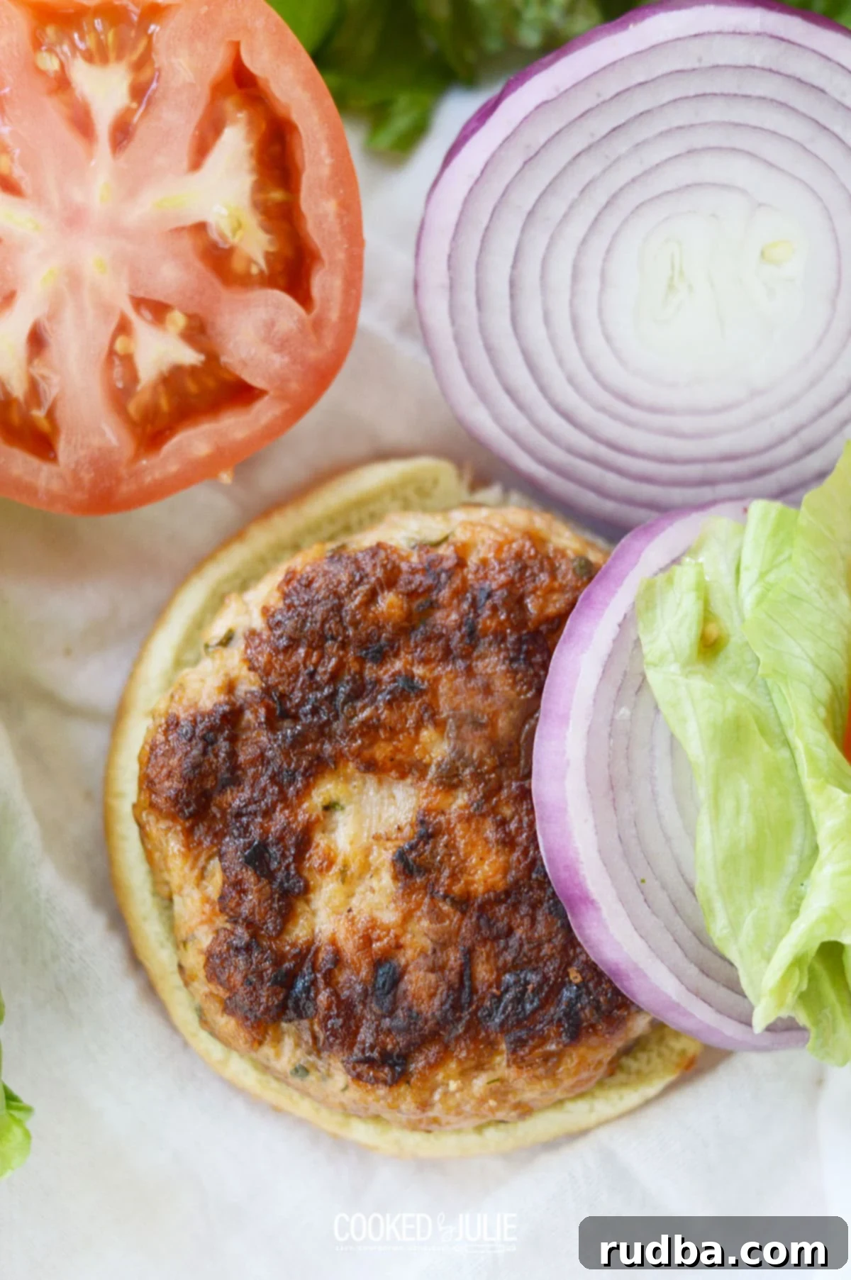 Delicious grilled salmon burger with lettuce, tomato, and onions on a bun