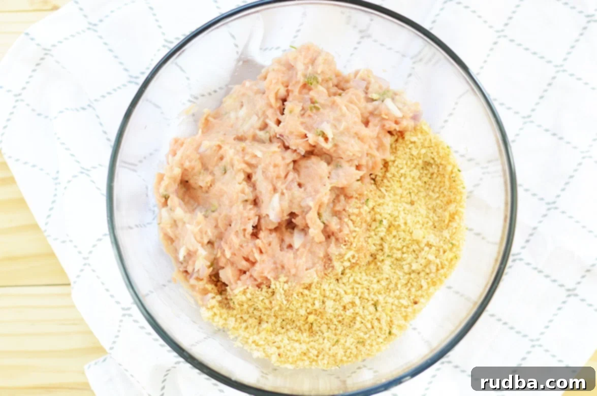 Salmon burger mixture and breadcrumbs in a clear mixing bowl