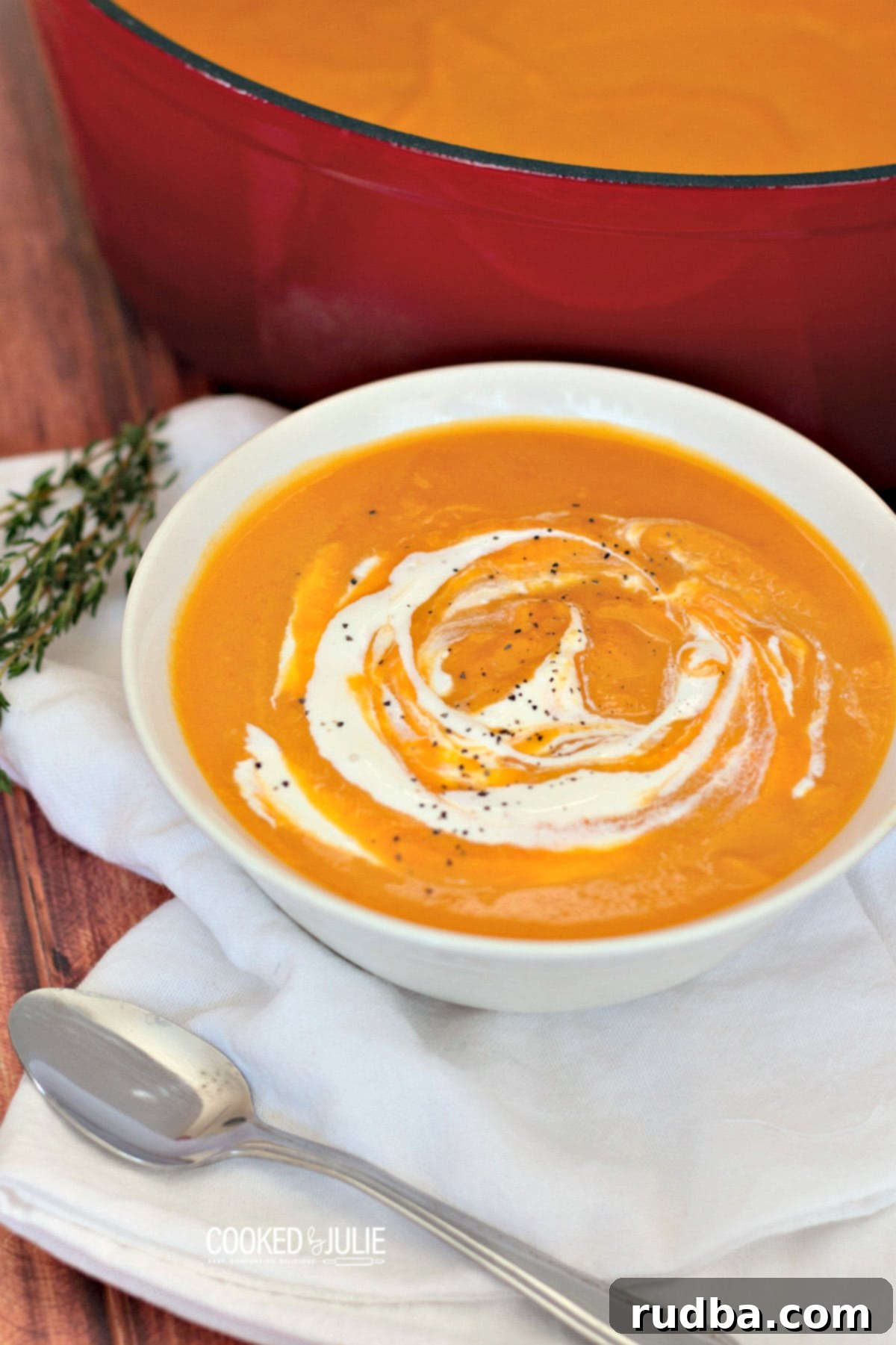 Creamy Roasted Butternut Squash Soup 2 Creamy roasted butternut squash soup served in a white bowl with a spoon, garnished with a swirl of cream and fresh herbs