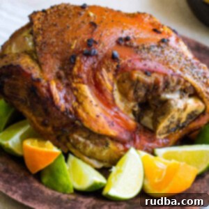 The Ultimate Cuban Pernil 5 roasted pork on a brown plate with limes and oranges
