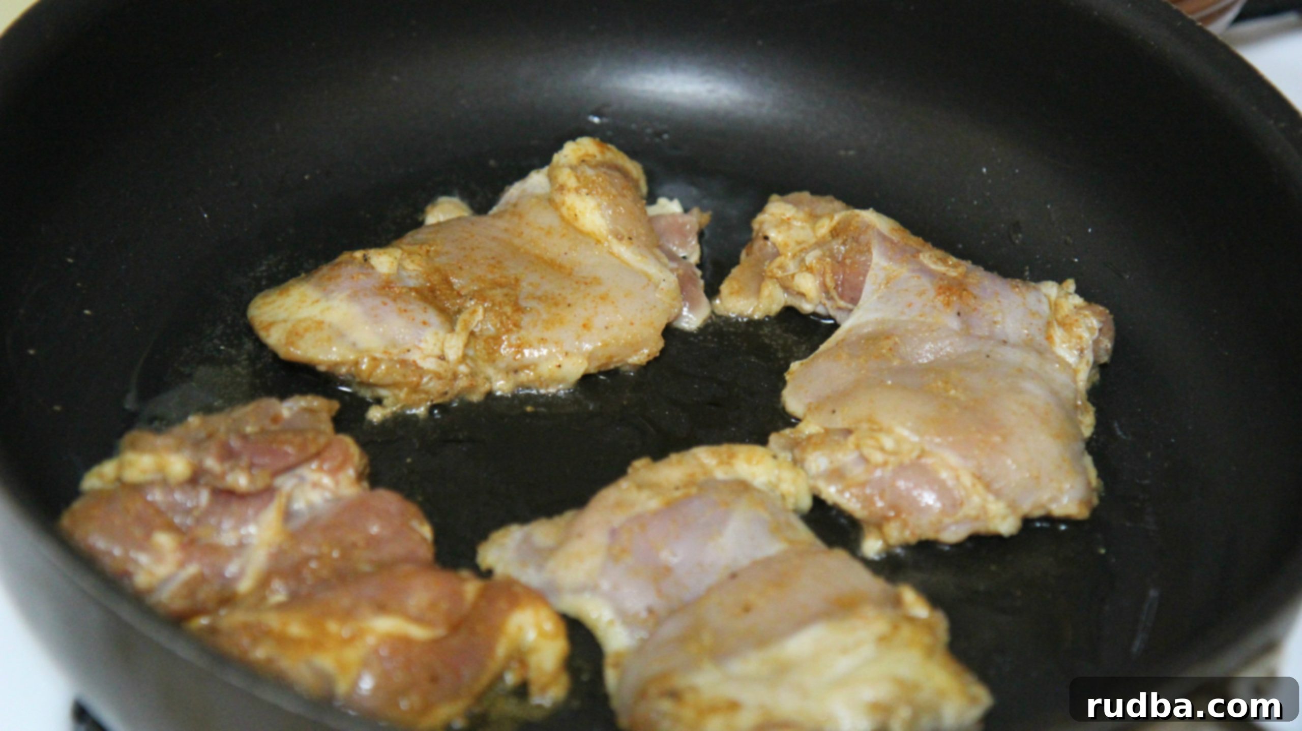 Chicken thighs in a skillet, perfectly seared and ready to be sliced for Halal Cart Chicken and Rice.