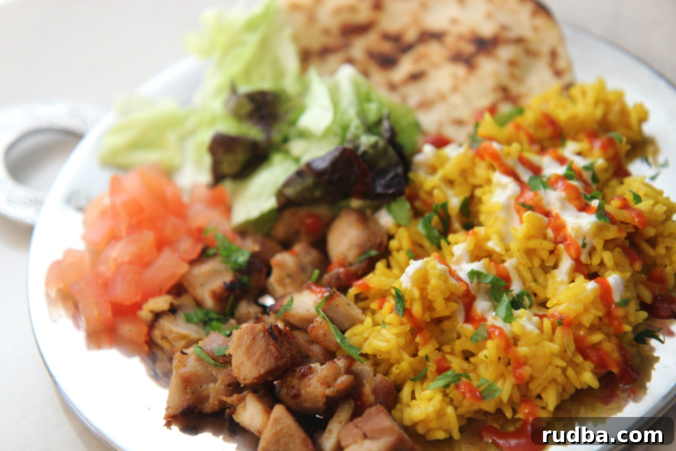 Halal Guys chicken and rice served with homemade white sauce, hot sauce, naan, fresh salad, and cilantro.