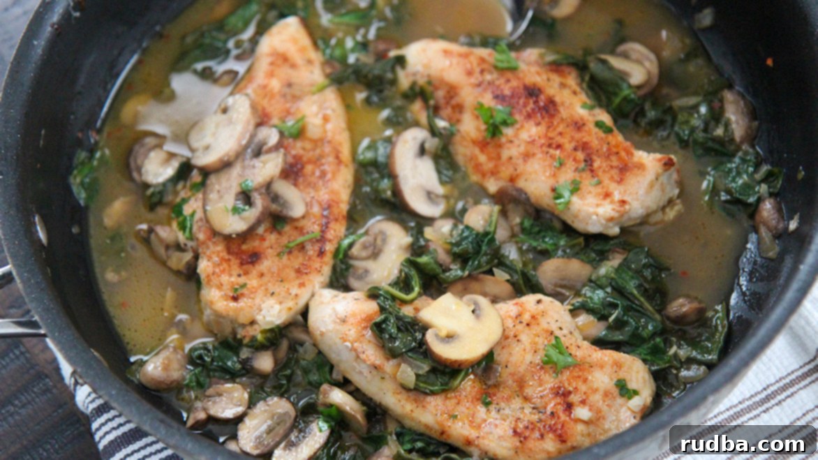 chicken, mushrooms, spinach, and sauce in a black skillet. 