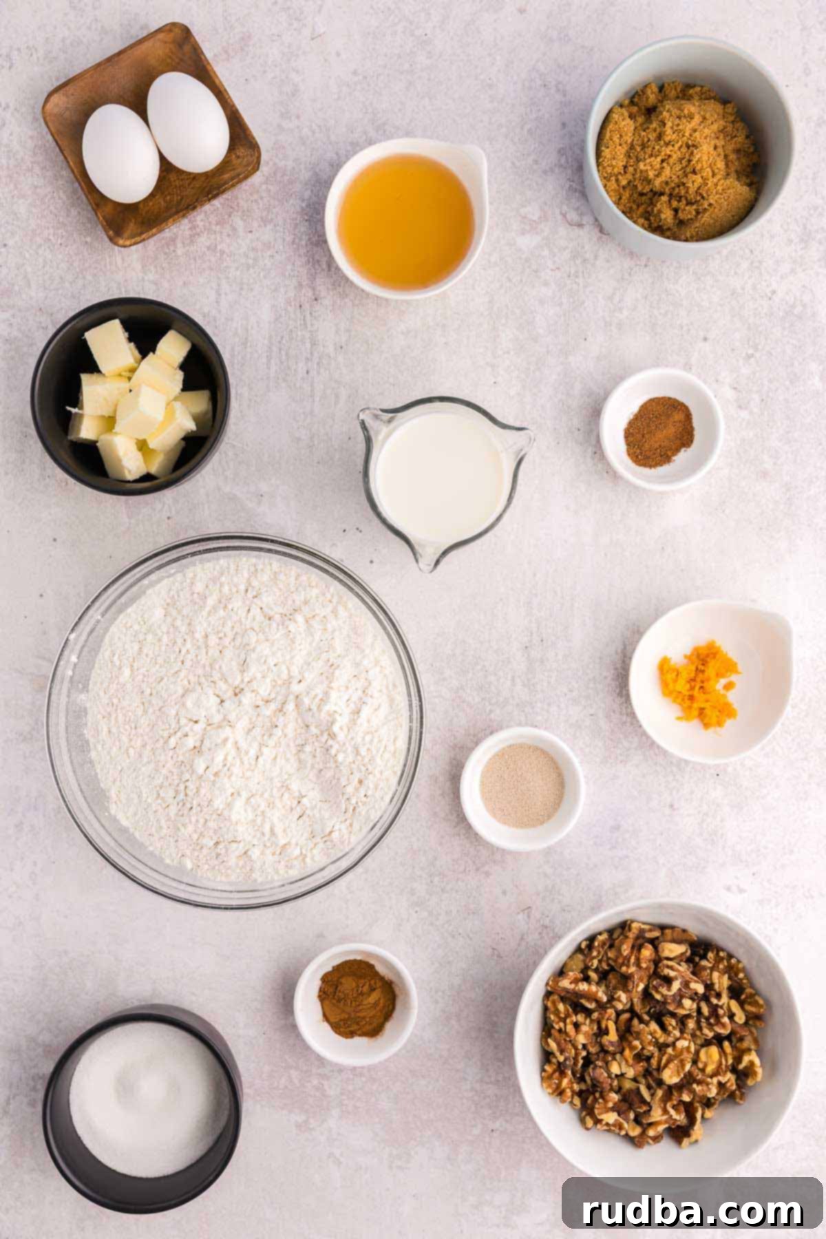 Close-up of fluffy dough being kneaded in a stand mixer, with additional baking ingredients for homemade sticky buns visible in the background.