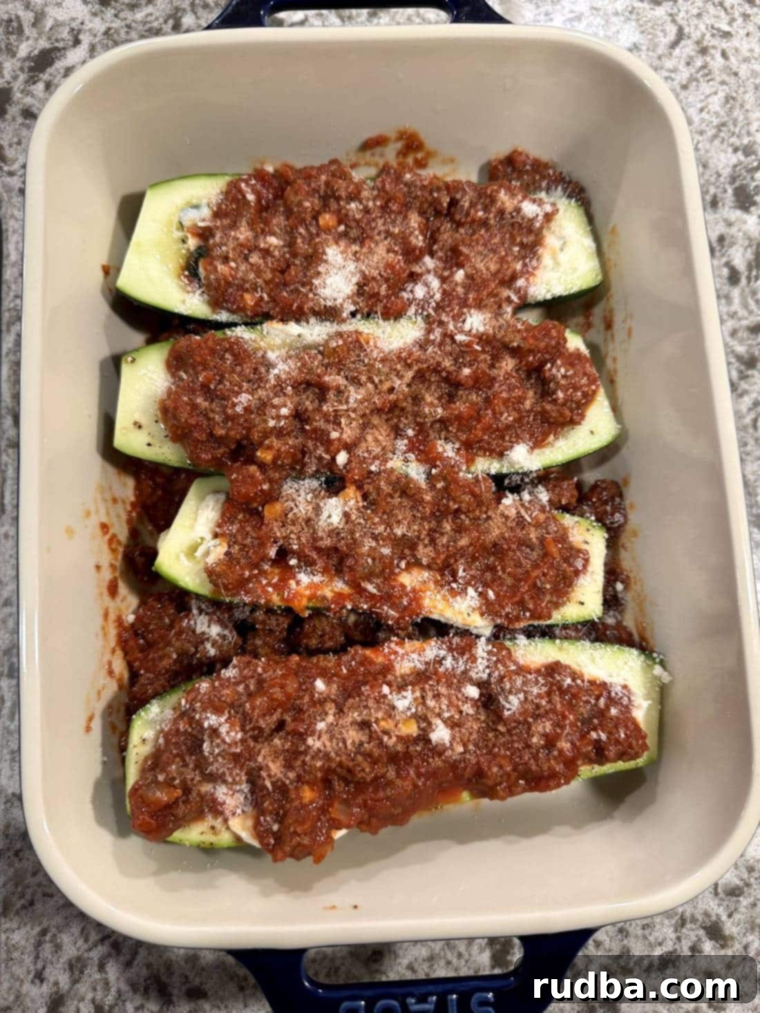 Lasagna-Filled Zucchini Vessels 4 Four zucchinis with meat sauce and parmesan cheese on top.