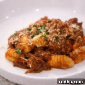Braised beef with gnocchi in tomato sauce, topped with parmesan and parsley.