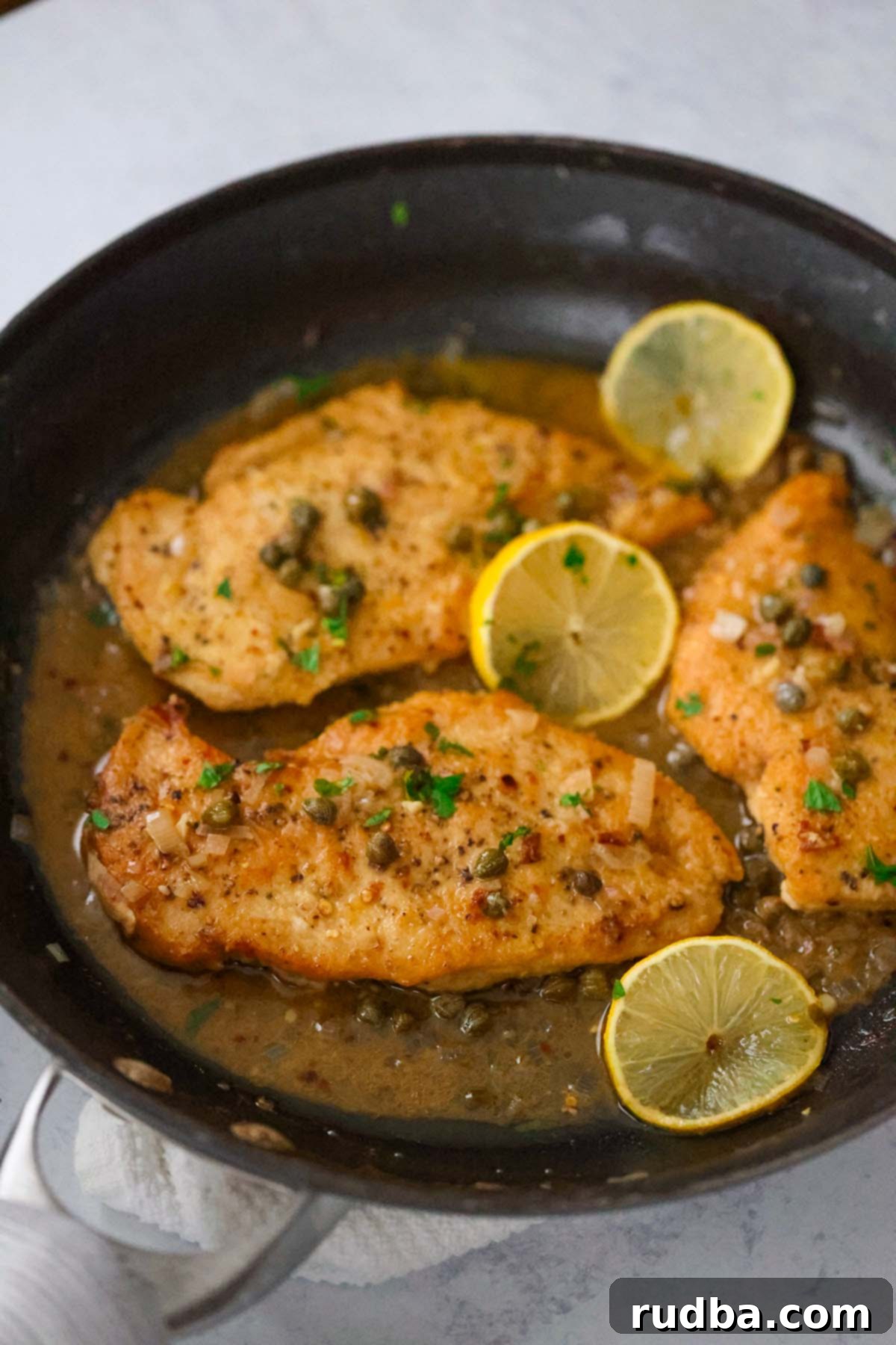 Effortless Chicken Dinners 2 Chicken piccata in a skillet with lemon slices.